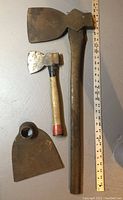 Antique broadhead axe, small hatchet, and hoe implement together with measuring tape for scale