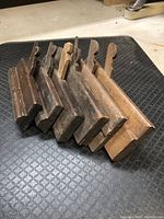Side view of six wooden molding planes stacked together, showing profile shapes and wood condition.