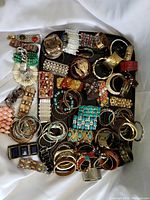 Top-down view showing assortment of bracelets including metal, resin, beaded and stretch styles in various colors and designs.