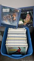 Blue plastic bin holding a stack of RCA CED discs in cardboard sleeves, with front covers of The Empire Strikes Back and Star Wars displayed.