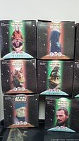 Front view of several Star Wars Episode I cube figurine boxes arranged in two tiers showing characters including Boss Nass, Jar Jar Binks, Yoda, and Anakin Skywalker.