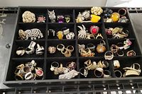 Top view of black sectioned tray with 55 assorted rings featuring multiple stones and designs