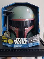 Front view of the Boba Fett electronic helmet in original packaging showing helmet design and Star Wars branding.