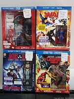 Four sealed Justice League Blu-Ray combo packs with included collectible figurines visible through packaging, each labeled with Best Buy price tags.