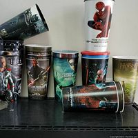 Overview of several large 3D cups featuring Spider-Man, Thor, Star Wars, Green Lantern, The Hobbit, and other movie themes stacked and positioned on a black shelf.
