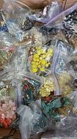 Multiple bags filled with different colorful necklace sets made of beads, chains, and plastic beads plus matching accessories.