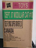 Cardboard shipping box labeled 'SES FLYING SUPER GROVER 2.0' and Hasbro logo on top, showing clear branding and product name.