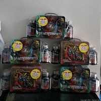 Full view of five sealed Transformers collector's lunchboxes, each paired with health supplement bottles.