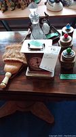 Overview of all lot contents including ink well stand, snail bottles, decanter, clock, jars and brush on wooden table