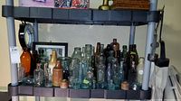 Wide shot showing multiple bottles on two shelves including different shapes and colors