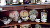 Overview of set displayed on wooden shelves showing plates, cups and serveware.