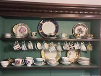 Shelf display of multiple china teacups, saucers, and plates in various styles and patterns