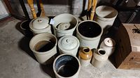 Nine stoneware crocks and jars arranged under table
