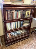 Front view of three stackable sections with glass drop-down doors filled with books