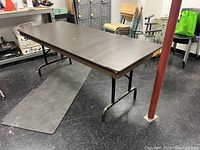 Side angle view showing the full length of the folding table with metal legs and laminate top