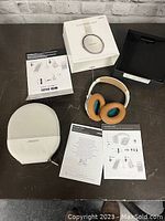 Full contents of the lot showing Bose SoundLink Bluetooth headphones with replacement tan ear cups, protective carrying case, original box, and instruction manuals.
