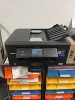 Front and top view of the Brother MFC-J880DW printer showing the paper input and output trays and touchscreen display on the front panel.