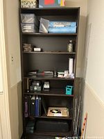Front view of a tall dark brown wooden bookcase with five shelves holding various items (not included in the lot).