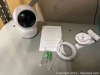 Image of the HeimVision HD smart Wi-Fi camera unit with accessories including user manual, Ethernet cable, mounting bracket, screws, and wall anchors on a tabletop.