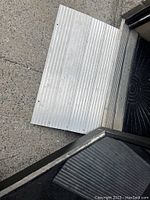 Metal portable mobility ramp placed on a threshold with ridged surface for traction