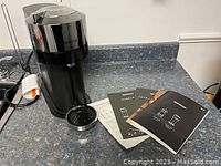 Nespresso coffee maker with front view, showing the machine and user manuals laid on countertop.