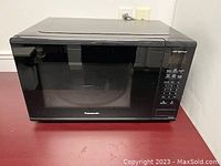 Front view of the Panasonic microwave showing its compact black rectangular design with glass door and control panel.