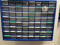 Blue plastic parts storage drawer with multiple small transparent drawers labeled for organization. Drawers include labels for screws, bolts, nails, washers, and other small hardware.