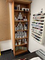 Front view of the wood effect bookcase filled with various paint cans and supplies (not included in sale).