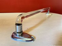 Close-up of chrome metal holder attached to bent clear glass rod showing Art Deco etched design and rounded glass end.