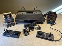 Photo of Atari 2600 console with all included game cartridges, two joystick controllers, paddle controller, switch box and power adapter.