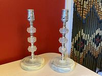 Pair of vintage bedside lamps with marbled Bakelite bases and faceted Lucite stems shown from front angle on wooden surface.