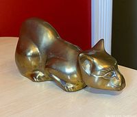 Front view of vintage brass cat figurine showing detailed facial features and body posture.