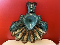 Close-up front view of the ceramic lobster chip and dip tray showing green and brown glaze, lobster claws, and scalloped chip section.