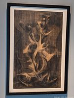 Framed surreal charcoal portrait artwork showing full piece at an angle against wall.