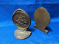 Front view of the two bronze bookends showing the nautical ship design and ornate rope border.