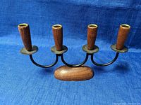 Front angled view of the four-arm candle holder showing wood holders on black metal arms and wooden base.