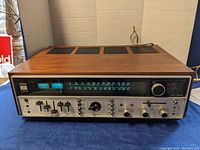 Front view showing wood veneer top and brushed aluminum front panel with tuning dial