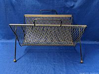 Side angle view of the vintage metal mesh magazine rack showing structure and handle