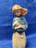 Close-up front view of the Nadal figurine showing the woman's face, shawl, and the lamb she is holding.