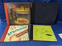 Four vintage jazz-related books and covers propped upright with different cover designs including The Lonesome Train and Drummin' with Krupa with other two blue and green covers.