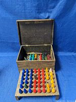 Wooden box open with colorful cone-shaped vintage glass bulbs inside and on a removable wooden tray insert.