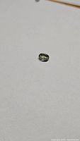 Close-up of the oval cut light mint green African sillimanite gemstone on white background showing clarity and color.