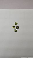 Four square cut apple green peridot gemstones on white background, showing clarity and cut details.