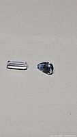 Photo of two loose aquamarine gemstones on a neutral background, one emerald cut rectangular and one pear-shaped cut, showing clarity and color.