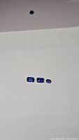 Image of three cushion cut cornflower blue kyanite gemstones arranged in a row on white background.