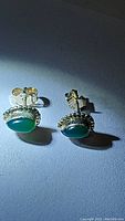 Photo of both green onyx sterling silver earrings on a flat surface showing size and color.