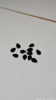 Photo of 11 pear-shaped jet black onyx checker cut gemstones arranged on a light surface