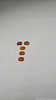 Five cushion cabochon Mexican caramel opal stones arranged in a vertical line on a white background, showing caramel color and smooth finish.
