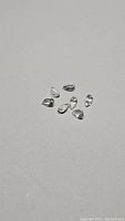 Seven light-colored pear cut rose quartz gemstones laid out on a flat surface, showing clarity and shape.