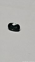 Oval cut teal green sapphire gemstone showing faceting and color.